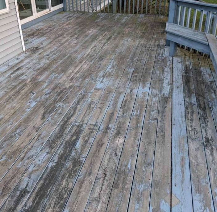 Wood deck with grey and blue finish peeling off the boards, bench and sliding doors in frame