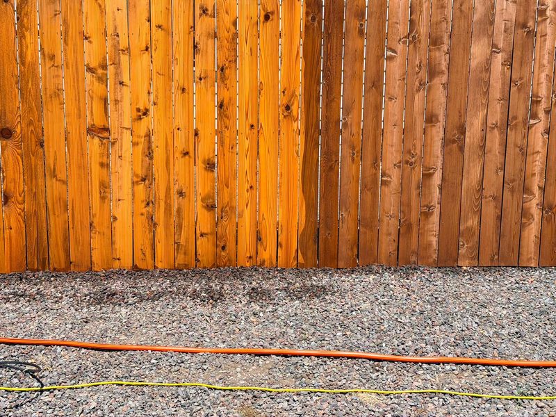 Close-up of cedar fence boards showing two sections in different stain tones