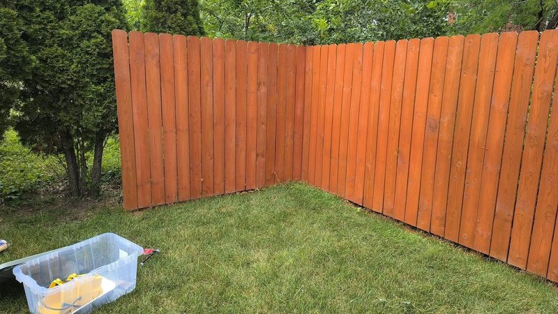 The same fence corner after a fresh redwood-tone stain